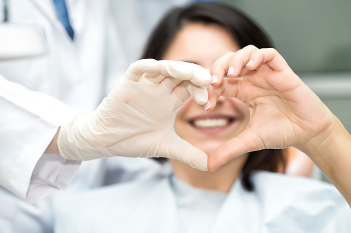 Arzt und Patientin formen mit den Händen ein Herz.